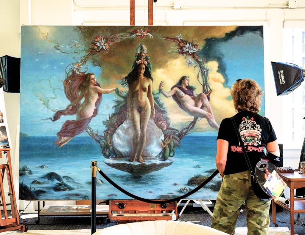 A visitor stands with their back to the camera while viewing a very large figurative painting displayed on an easel.