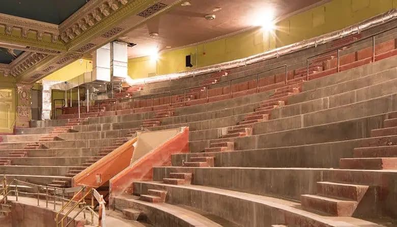 The Coliseum Theatre's upper balcony as it stands today, packed with HVAC equipment from its retail decades, with original gilded plaster ornament still visible above