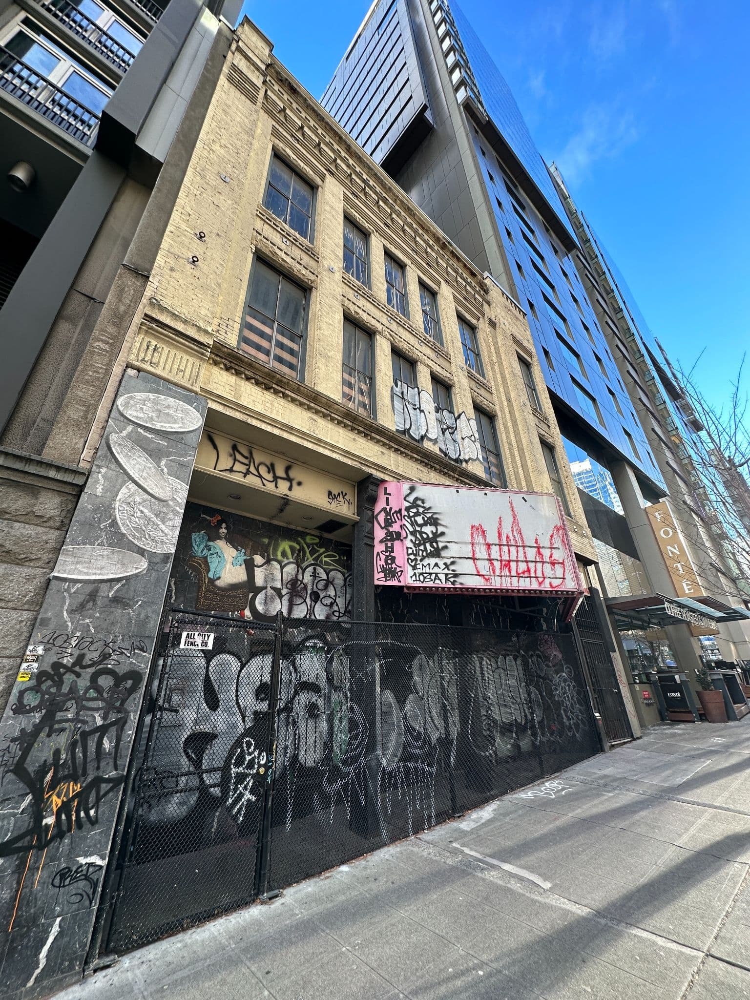 The Lusty Lady building exterior on 1st Avenue, Seattle, in 2022: the original yellow-brick three-story facade is intact above, with the marquee removed and the lower storefront covered in tagged graffiti